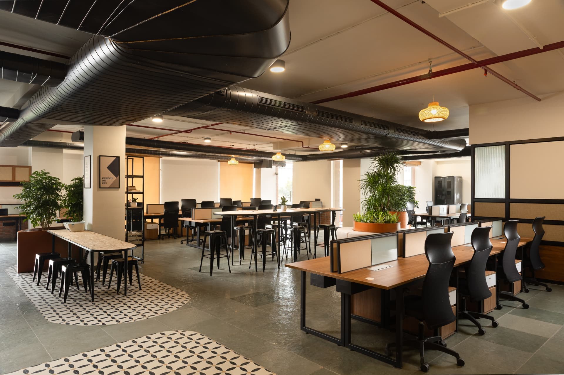 Open workspace floor at Steadwork with timber desks, high tables, exposed services and planting